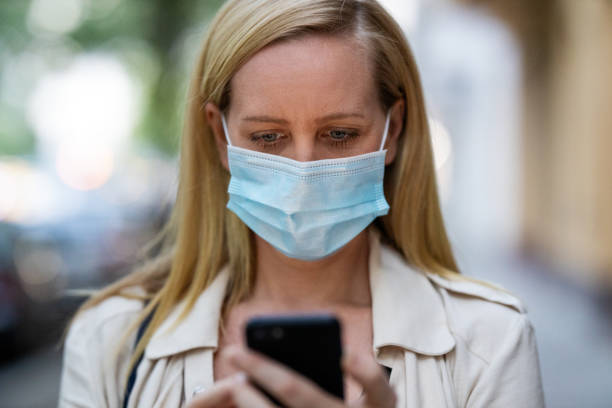 istock Woman with mask using her phone in the city 1254026662