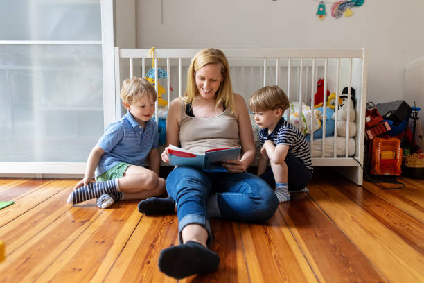 mãe com dois filhos lendo um livro em casa - three people adults germany berlin germany - fotografias e filmes do acervo