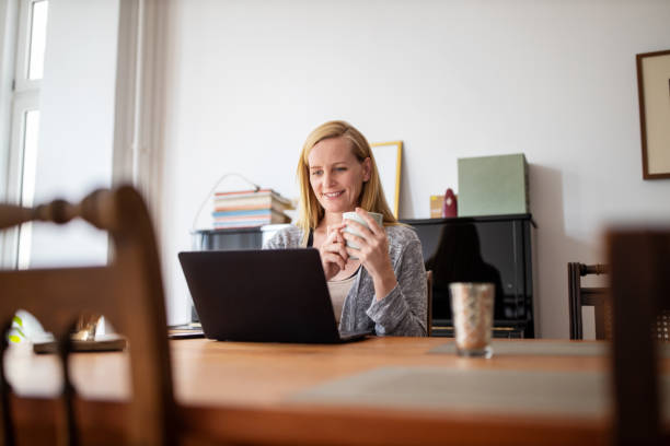 istock Woman having coffee and using laptop at home 1254026988