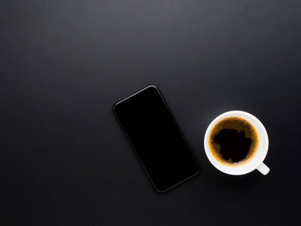 istock Smartphone and coffee on black office desk. 1254028422