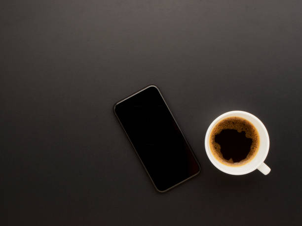 istock Smartphone and coffee on black office desk. 1254028438