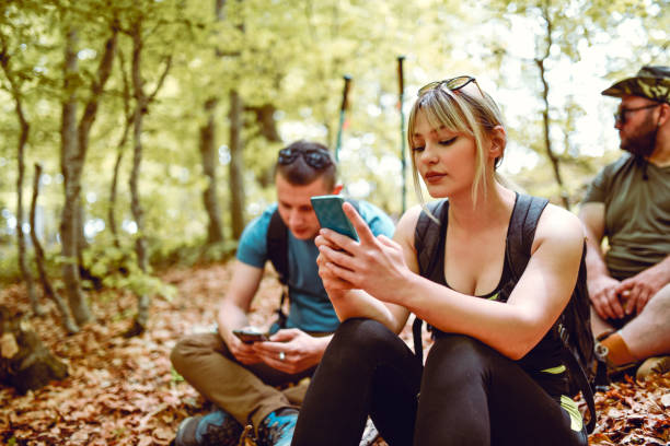 istock Female Looking Through Smartphone While Resting From Hiking With Friends In Forest 1254028942