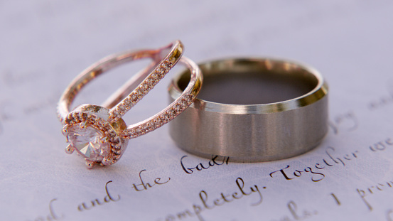 Shot of two wedding rings on top of a piece of paper with handwriting on it