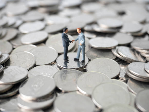 istock money, coins stack, two miniature businessman handshaking 1254035961