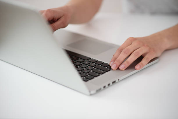 istock Girl uses a laptop on a white table. Type on a keyboard. Remote work on freelance. 1254036623