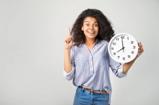 portrait of a beautiful african woman with a clock on grey backround - clock face fotos imagens e fotografias de stock