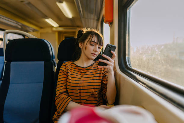 jeune femme sur un train utilisant le téléphone portable - telephone window mobile phone addiction photos et images de collection