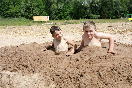 Two kids playing on sandy beach of Lake Seliger, Ostashkov, Russia