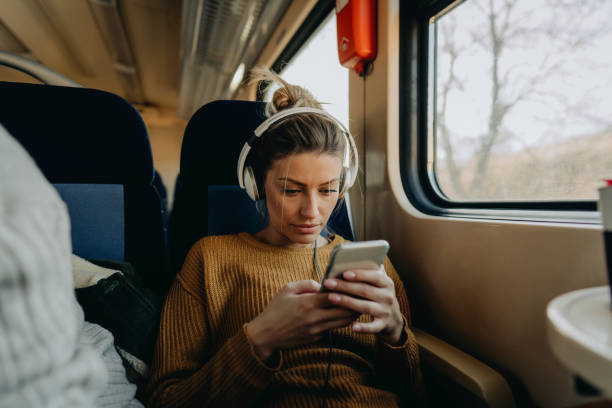 jeune femme sur un train utilisant le téléphone portable - telephone window mobile phone addiction photos et images de collection