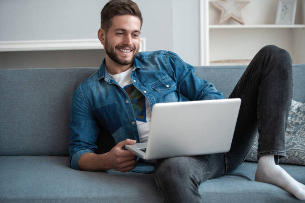 istock Smiling young man making video call with friends at his modern home 1254047601