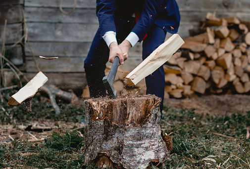 firewood and an axe. A man in a jacket chopping wood. Businessman on holiday in nature.