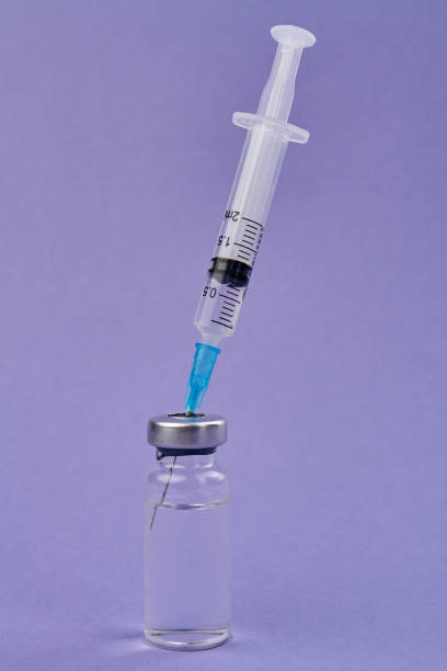 istock Syringe inserted into and medicine vial. 1254048504