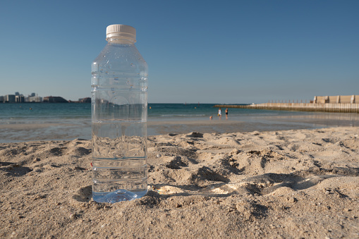 Closeup to bottle of water on the beach. Representation of pollution of the beach area.