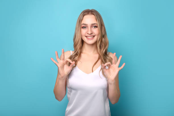 istock Beautiful woman using sign language on blue background. Sign language 1254050558