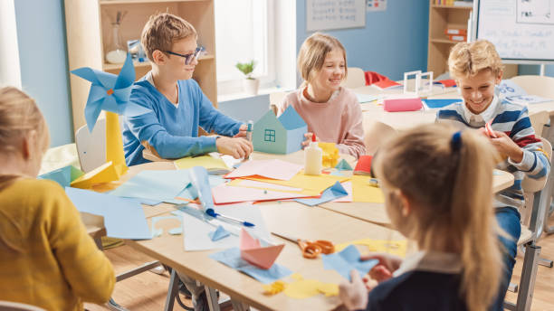 istock Elementary School Arts & Crafts Class: Diverse Group of Smart Children Have Fun on a Handicraft Project, Using Colorful Paper, Scissors and Glue to Create Fun Papier Mache. 1254050832