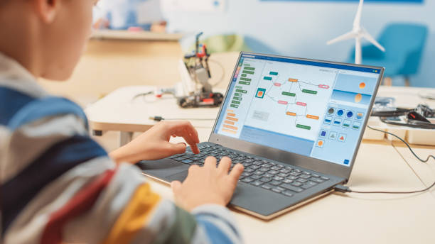 smart schoolboy maakt gebruik van laptop om software te programmeren voor robotica engineering class. elementary school science classroom met begaafde briljante kinderen werken met technologie - code stockfoto's en -beelden