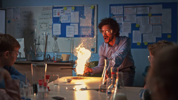 school chemistry classroom: engrossed children watch how enthusiastic teacher shows science experiment by setting powder on fire creating beautiful fireworks. kids getting fun modern education - professor scientist chemistry teacher imagens e fotografias de stock