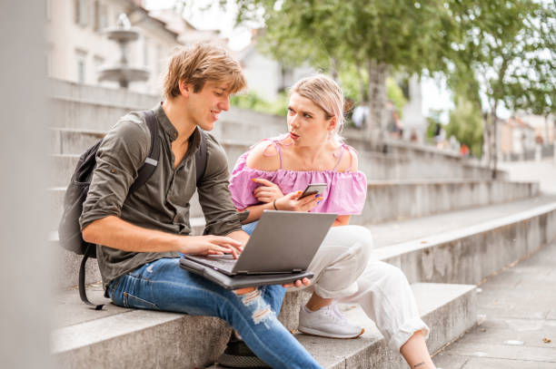 istock Young couple using a laptop on the staircase in a city 1254053619