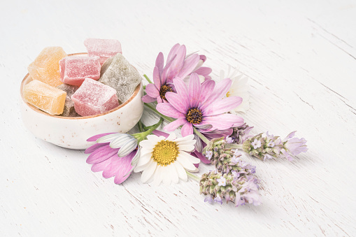 colorful Turkish delights and spring flowers on a wooden table with copy space