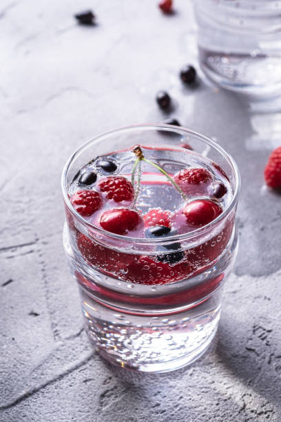 istock Fresh cold sparkling water drink with cherry, raspberry and currant berries in two transparent glass on stone concrete background, summer diet beverage, angle view macro 1254056680