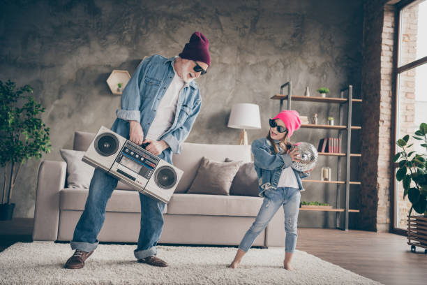 foto de duas pessoas funky vovô neta pequena legal elegante elegante sun specs jeans roupa festa casa ouvir gravador gravador ficar casa quarentena sala de estar dentro de casa - listening child grandfather family - fotografias e filmes do acervo