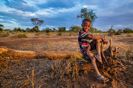 African little boy from Masai tribe playing on savanna, Kenya, East Africa. Maasai tribe inhabiting southern Kenya and northern Tanzania, and they are related to the Samburu.