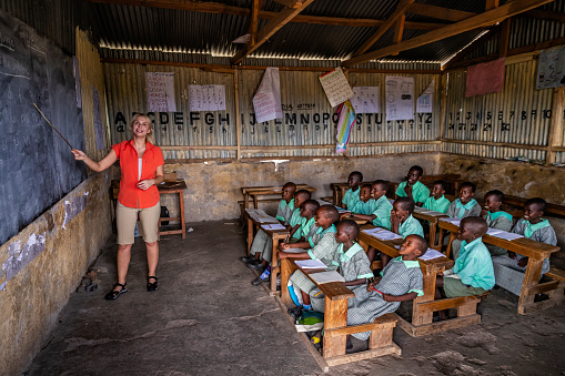 Caucasian female volunteer teaching in Africa, school near Masai Mara Game Reserve in Kenya.