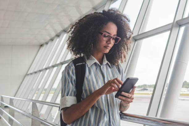 istock Young woman with backpack checking her boarding schedule at the airport 1254058337