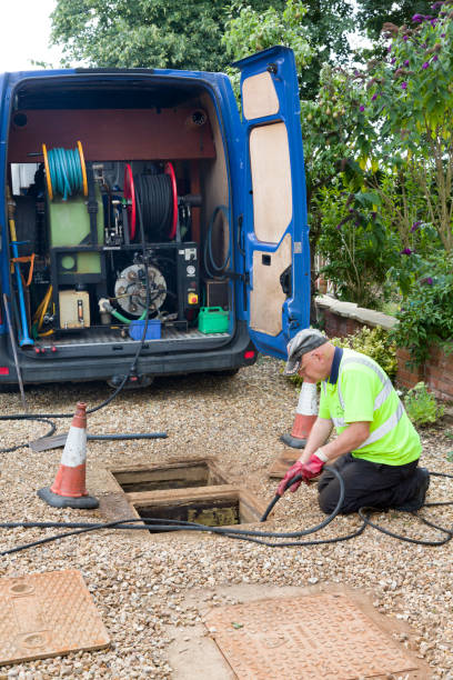 Drain cleaning company jetting sewage drain, UK Buckingham, UK - August 07, 2015. Drain cleaning company, man jetting sewage drain outside house, UK jetting stock pictures, royalty-free photos & images