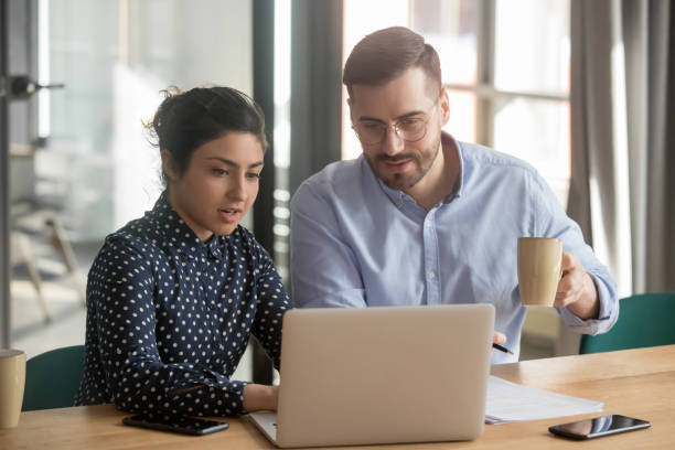 istock Helpful indian female mentor explaining online project to male intern 1254063667