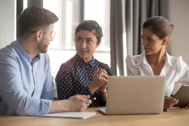 istock Indian female mentor helping interns coworkers explain computer work 1254063679