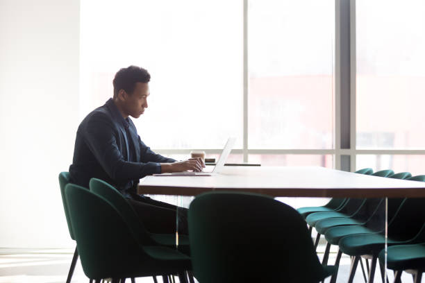 istock Focused african businessman working on laptop sit at conference table 1254063694