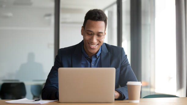 istock Happy african businessman working using laptop sit at office desk 1254063720