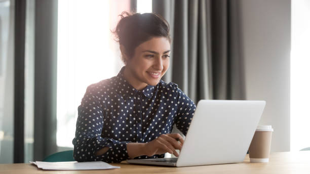 istock Happy young indian businesswoman using computer sit at office desk 1254063729
