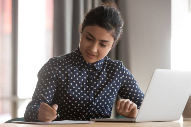 istock Young indian businesswoman student working studying with laptop making notes 1254063733