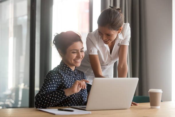 istock Friendly caucasian mentor supervise indian intern secretary helping with computer 1254063745