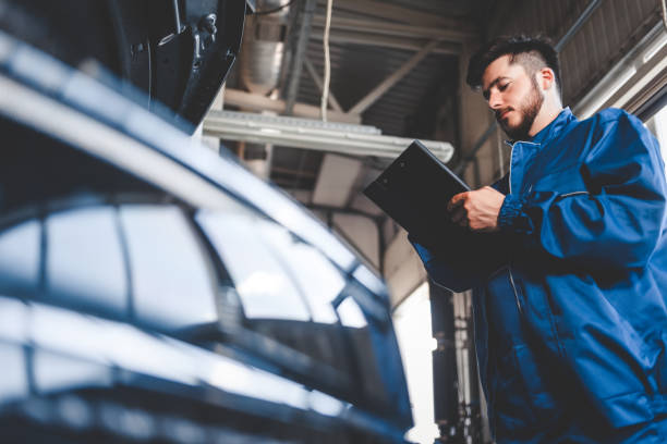 자동차 정비사는 클립보드에 수리 계획을 작성합니다. 자동 서비스 근로자 남성 - auto repair shop adult auto mechanic blue 뉴스 사진 이미지