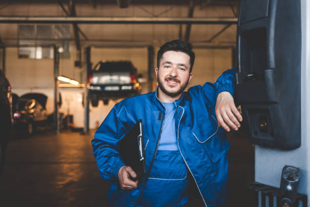 portrait of a positive car mechanic in a garage - auto repair shop adult auto mechanic blue imagens e fotografias de stock