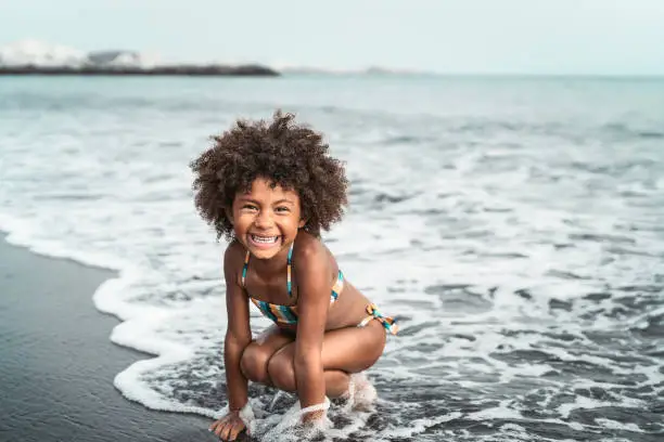 Photo of Afro American child having fun on the beach - Little kid playing during summer time outdoor - Black people and vacation concept