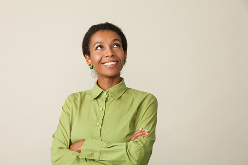close-up studio portrait of a 33 year old african american woman in green shirt on beige background