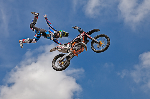 Freestyle motocross, a stunt biker make a jump and performing an acrobatic figure in flight, during the motorcycle rally Motosalsicciata. Voltana di Lugo, RA, Italy - April 10, 2016