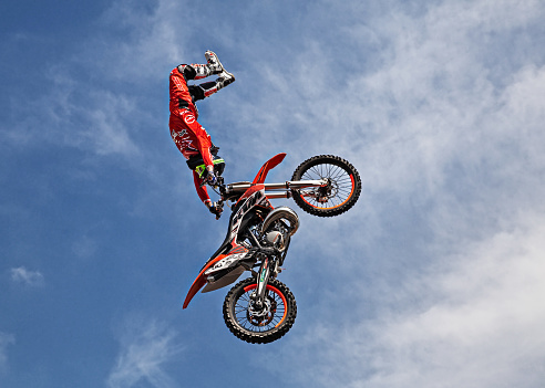 Extreme sports, motorcycle jumping. Motorcyclist makes an extreme jump against the sky. Extreme sports, motorcycle jumping. Motorcyclist makes an extreme jump against the sky. Special processing under the film with flare