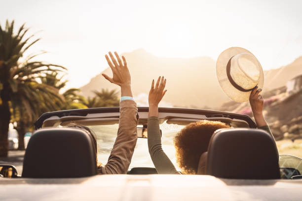 jeunes couples heureux faisant le voyage de route dans la ville tropicale - les gens de voyage ayant l’amusement conduisant dans la voiture décapotable à la mode découvrant de nouveaux endroits - concept de mode de vie de vacances de relation et de je - romance women behavior summer photos et images de collection