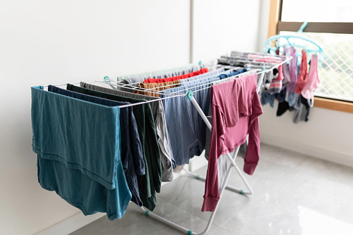 Woman hanging clean laundry with clothespins on washing line in mountains, back view