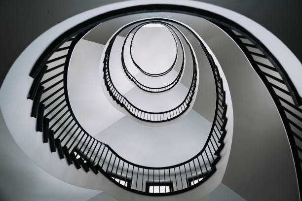 istock looking deep into long spiral stair case of big building 1254077913