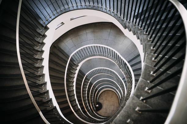 istock looking deep into long spiral stair case of big building 1254077920
