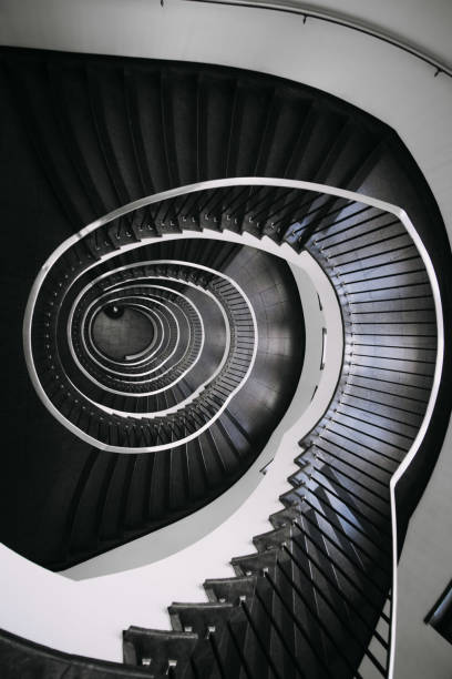 istock looking deep into long spiral stair case of big building 1254077954