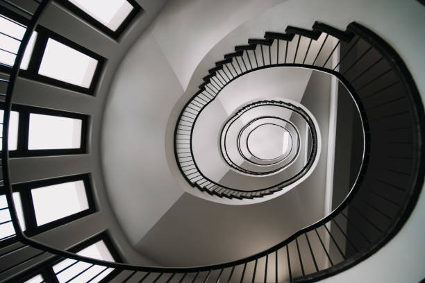 istock looking deep into long spiral stair case of big building 1254077993