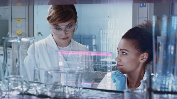 istock Multi ethnic female team studying DNA mutations. Virtual touch screens 1254080275