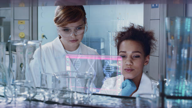 istock Multi ethnic female team studying DNA mutations. Virtual touch screens 1254080333
